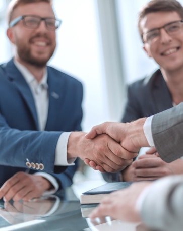Poignée de main professionnelle lors d'un accord d'affaires Poignée de main entre deux hommes d'affaires souriants en costume lors d'une réunion de bureau.