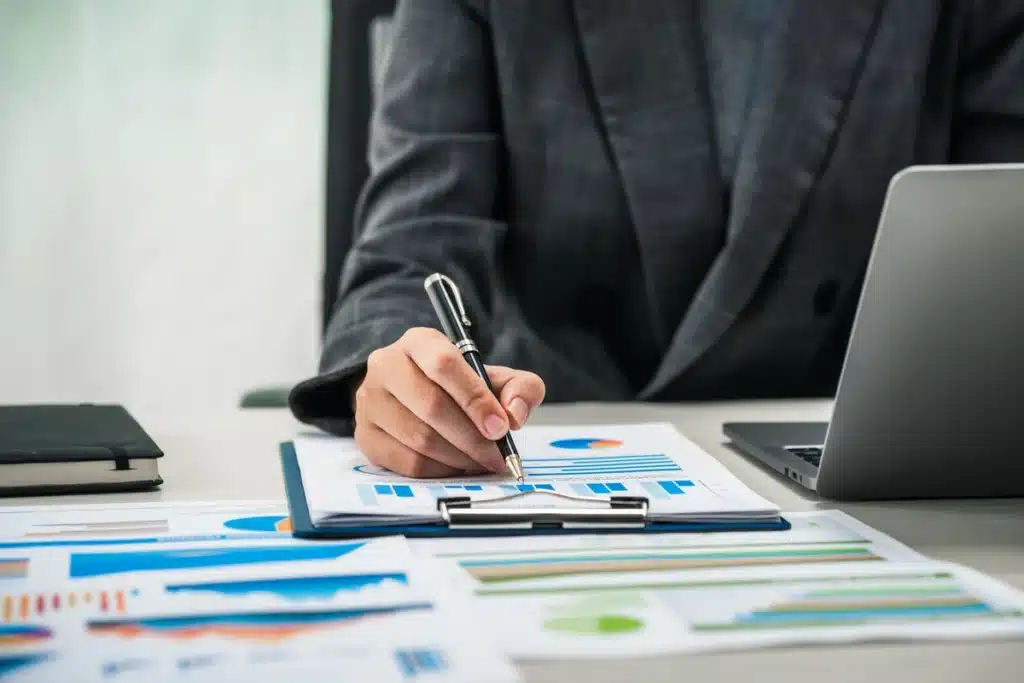 directeur-financier-stylo Un professionnel analysant des graphiques financiers et des tableaux de bord sur un bureau, illustrant le rôle stratégique d’un directeur financier dans la supervision des performances de l’entreprise.